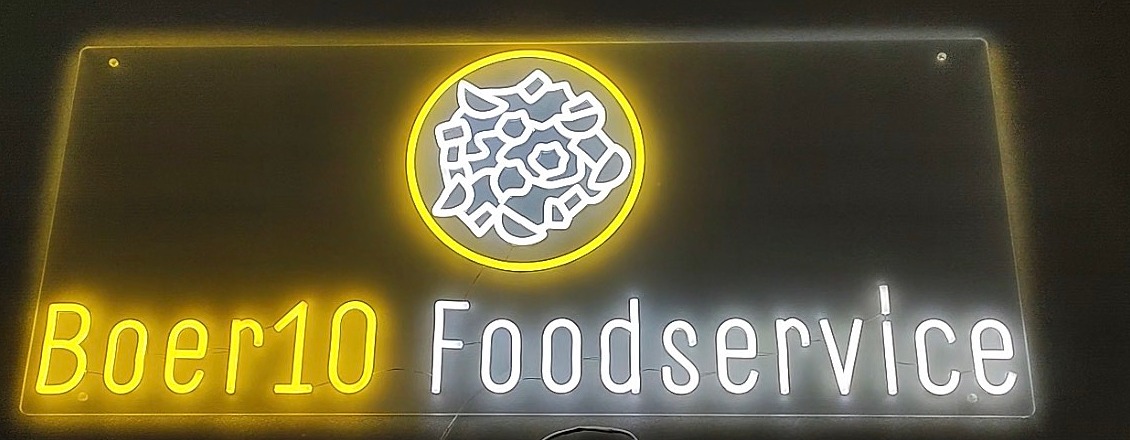 Het neonbord van Boer10 Foodservice van dichtbij: geel en wit neon op een transparante plaat