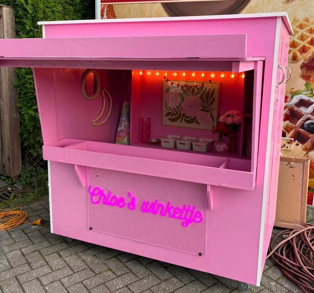 Roze neon naambord Chloe's winkeltje op een roze houten kraampje in Amsterdam