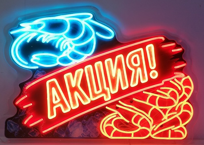 Neon actiebord voor een viskraam: een garnaal in blauw neon, garnalen in geel en een rode banner, op een bedrukte achterplaat